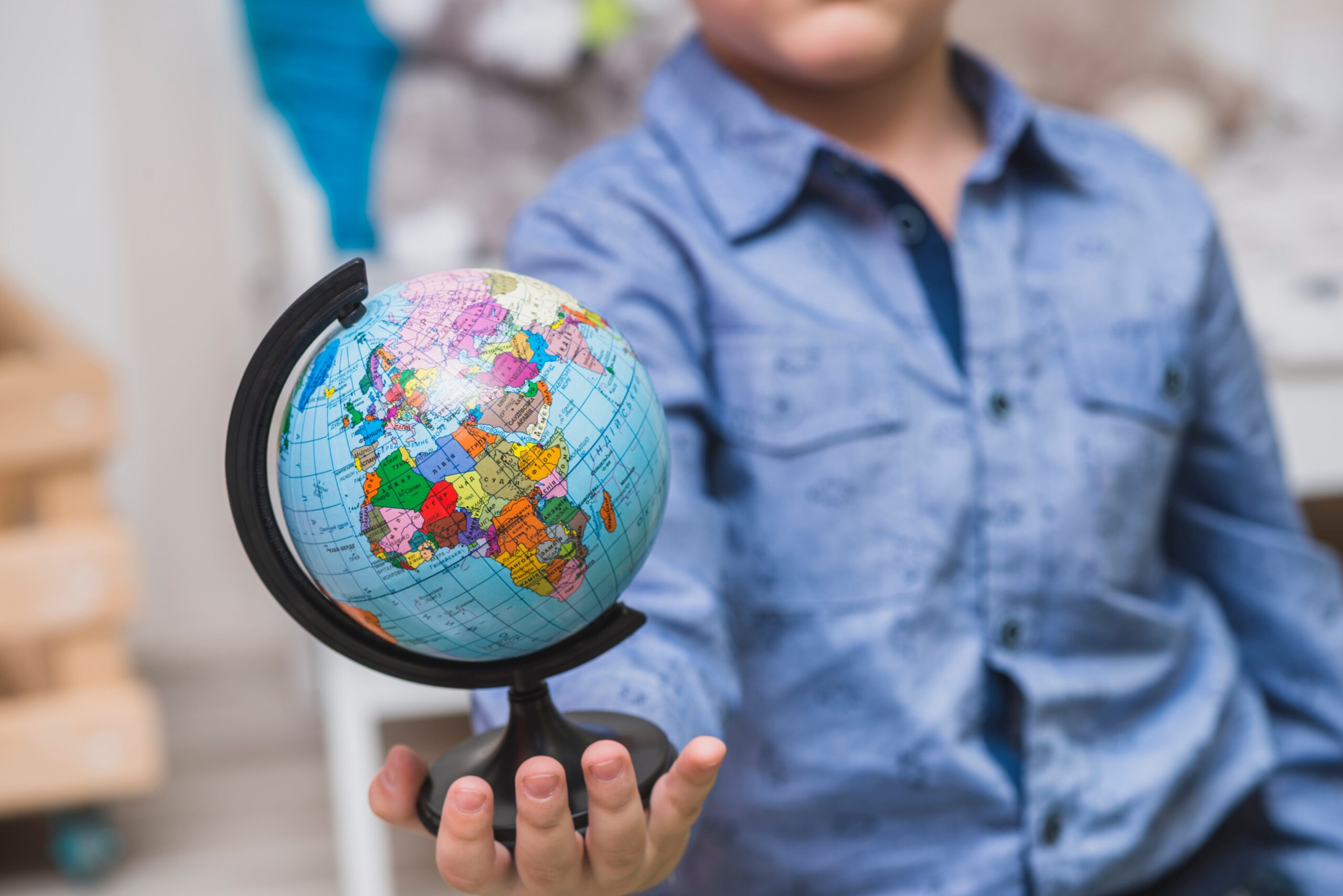 A man holding out a small globe