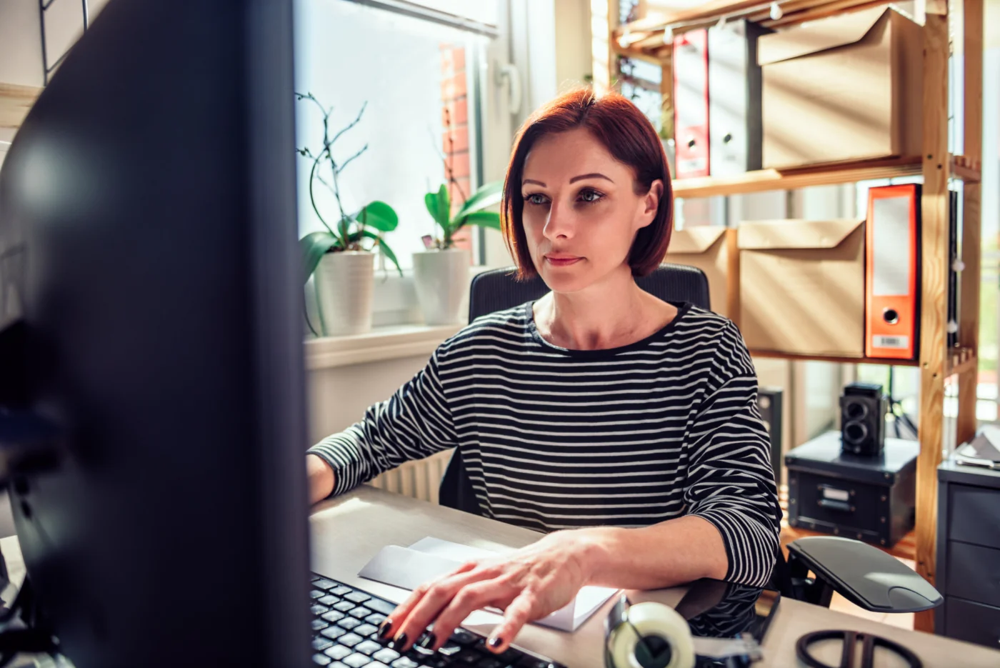 A one-person business owner working at a computer in their own office