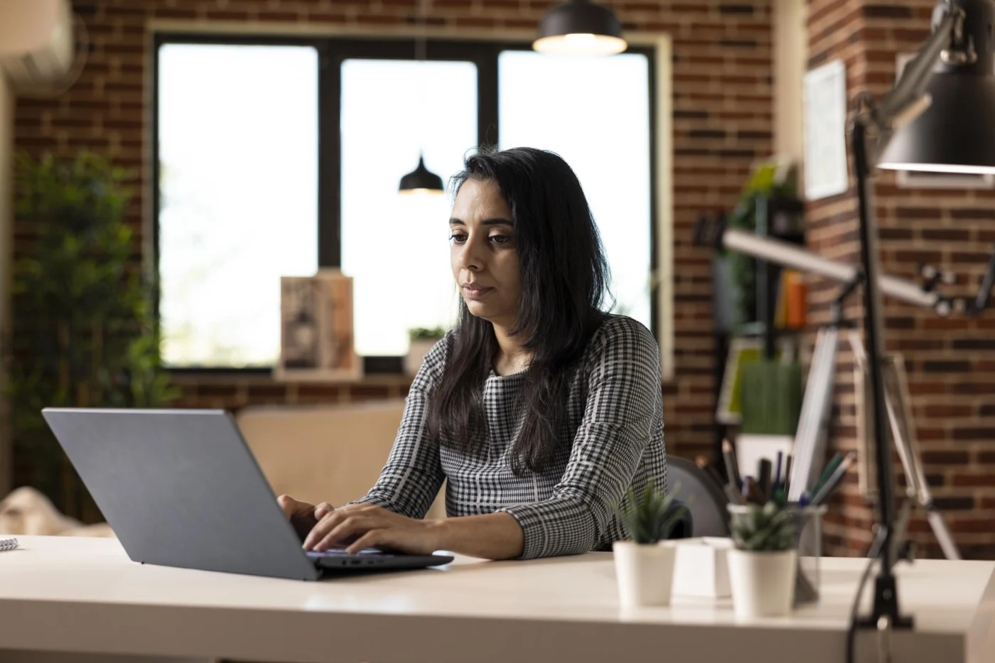 An independent professional working at a laptop in their own workspace