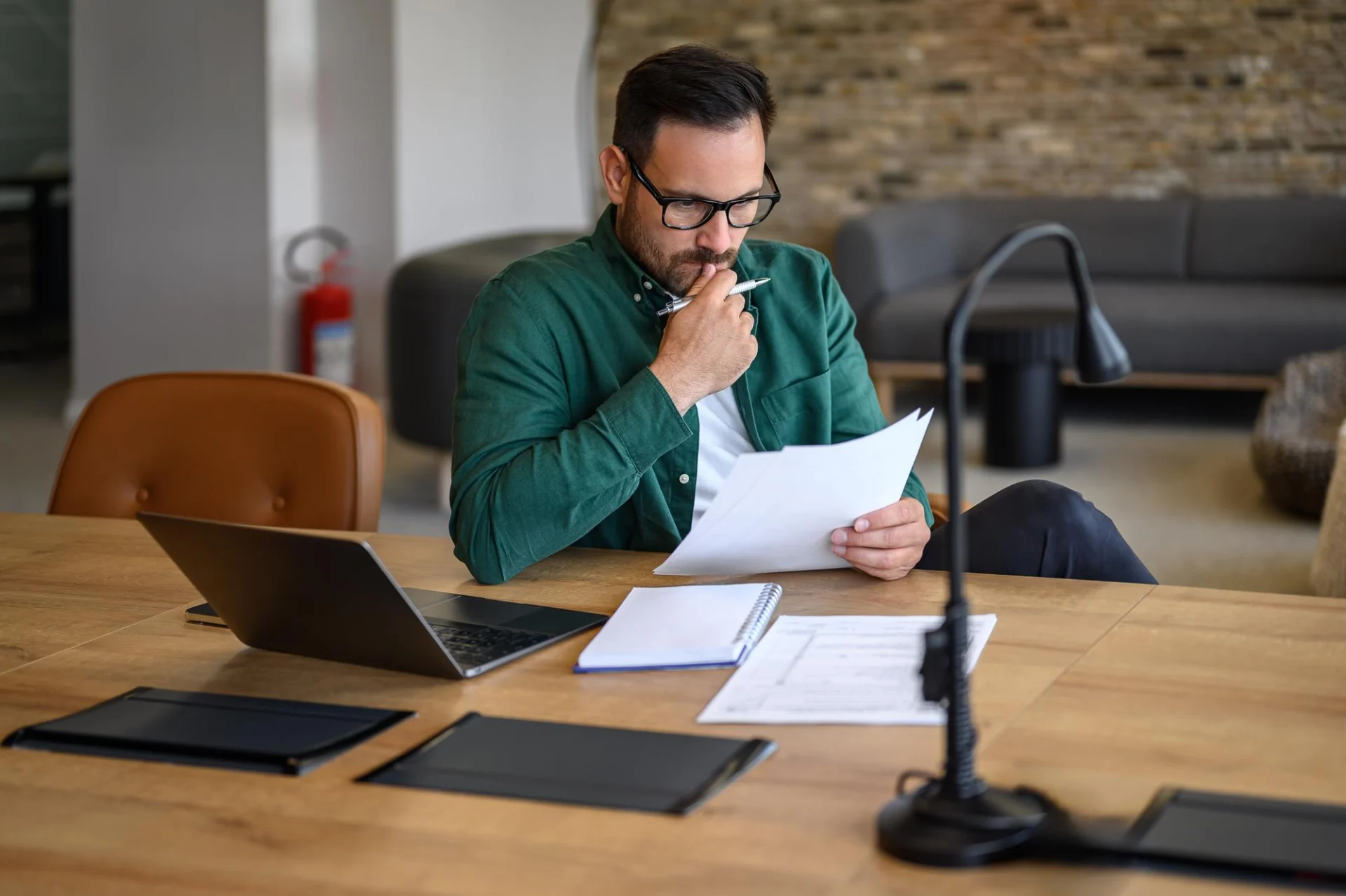 An independent professional weighing up a decision over a document at their desk