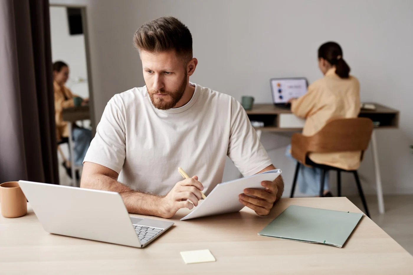 Young professional making detailed notes while reviewing a laptop screen